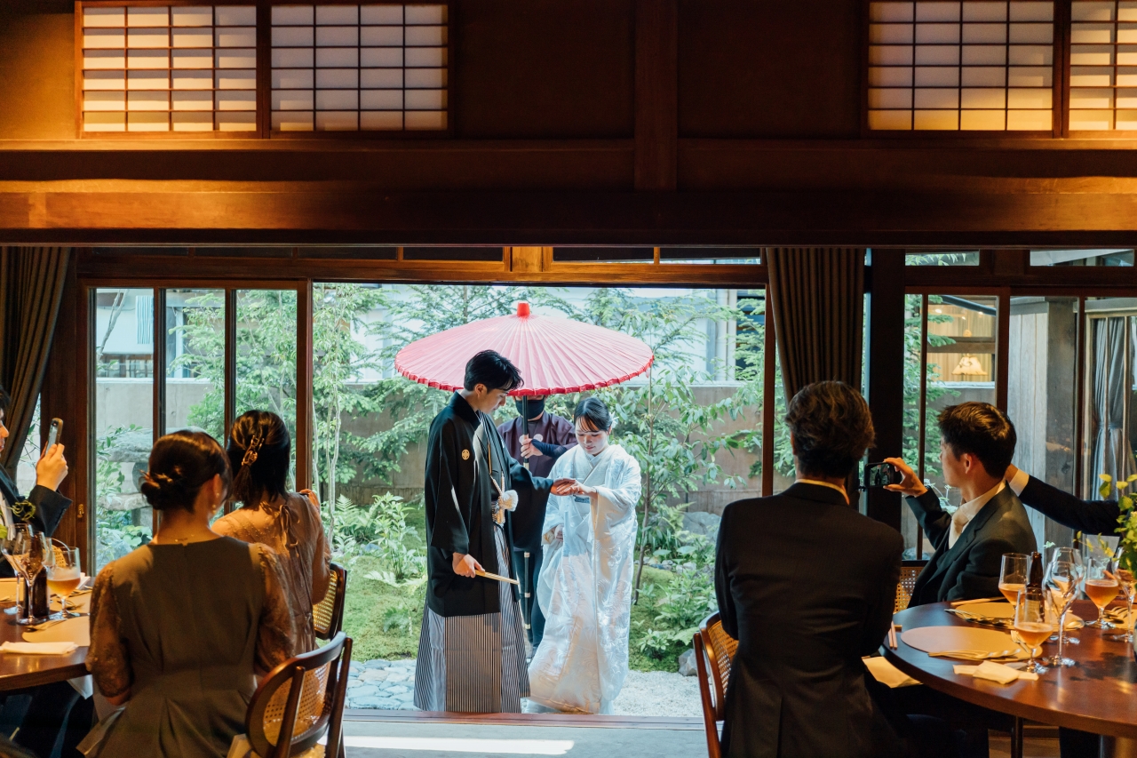 三河屋本店の俥夫演出で新郎新婦を赤の大番傘でお供する様子